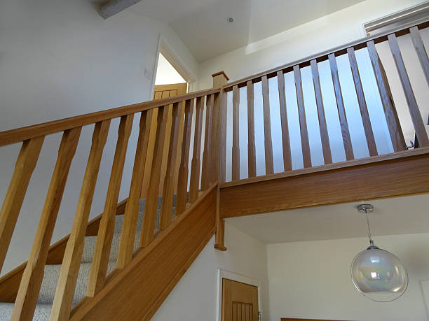 Image of modern, light-oak stair spindles / wooden staircase balusters, hallway Photo showing some modern light oak, straight wooden staircase spindles / balustrades, which are pictured in the hallway of a domestic house, creating a grand entrance.  This oak balustrading has just been fitted, complete with matching handrails, baserails and skirting boards, and a pale beige, cream carpet on the steps / stairs. baluster stock pictures, royalty-free photos & images
