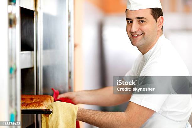 Smiling Baker Taking Out Pan Of Pastry From The Oven Stock Photo - Download Image Now