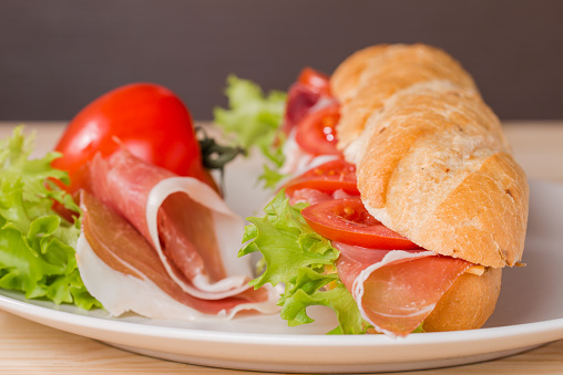 Ham and cheese salad submarine sandwich from fresh baguette on plate