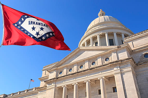 Arkansas flag flying high beside the State Capitol Building State Capitol Building front exterior in Little Rock Arkansas with US state flag outside on clear windy day with blue sky. arkansas stock pictures, royalty-free photos & images