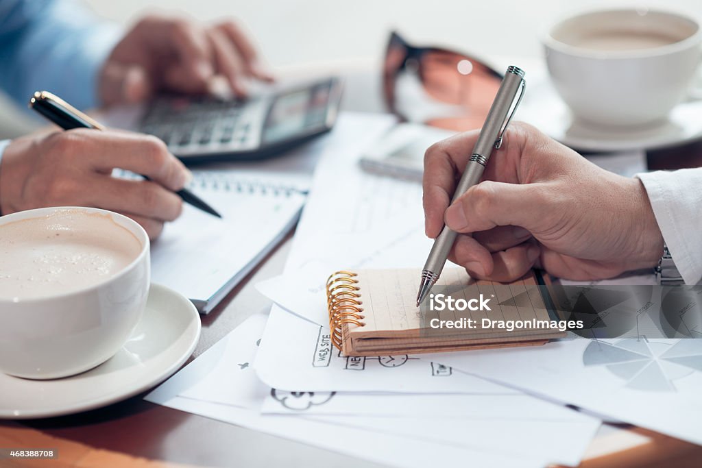 The hands of 2 men jotting in notepads at work Business partners planning their work 2015 Stock Photo