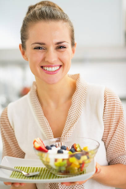 Smiling young woman holding fresh fruit salad