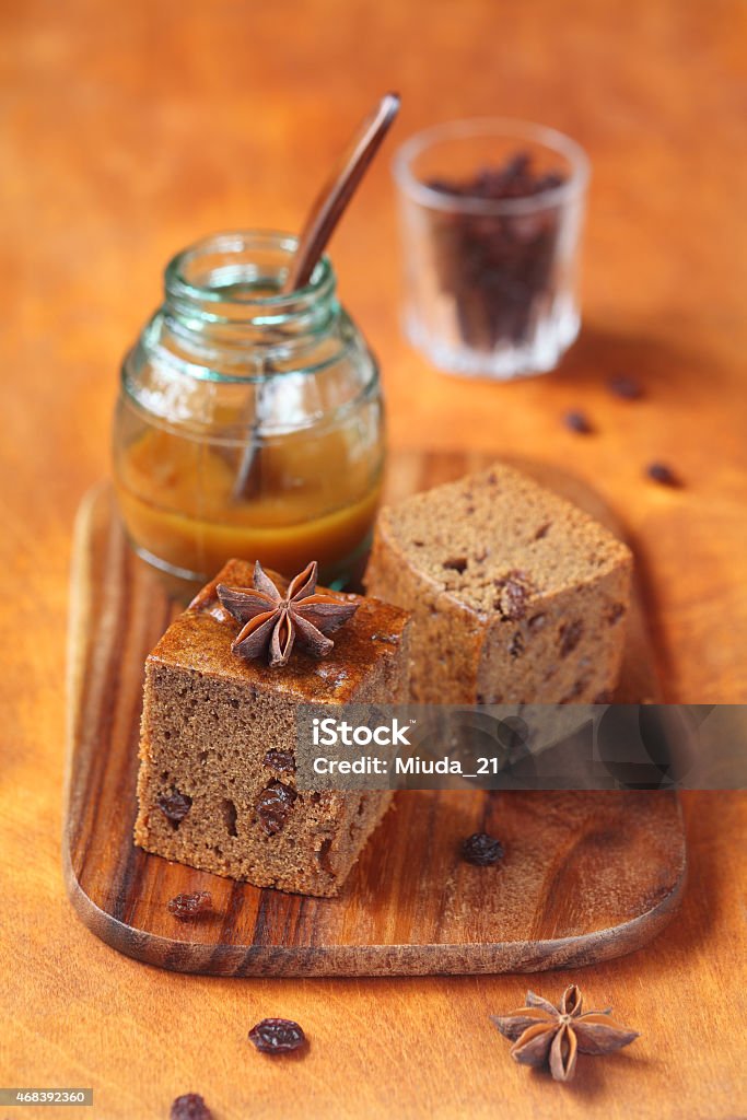 Two squares of Vegetarian Honey Coffee Cake with Raisins Two squares of Vegetarian Honey Coffee Cake with Raisins and a pot of honey, on a wooden cutting board and table. Cake Stock Photo