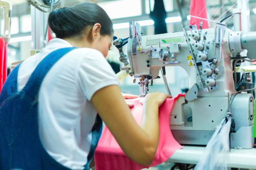 Asian Seamstress or worker in a Indonesian factory sewing with a industrial sewing machine, she is very accurate