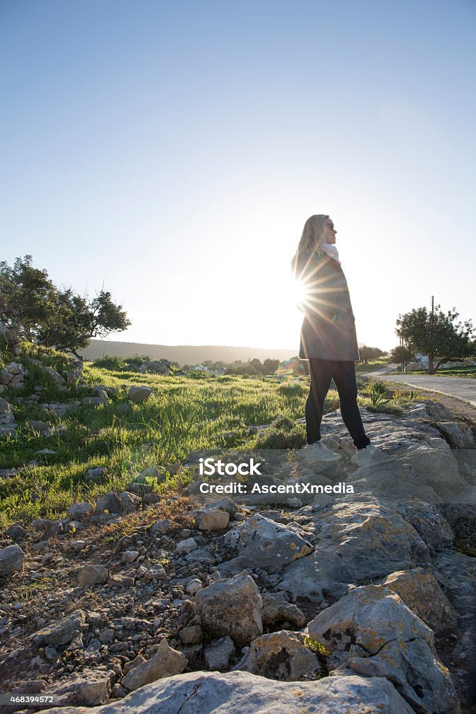 Woman stands on rock wall above road, sunrise 2015 Stock Photo