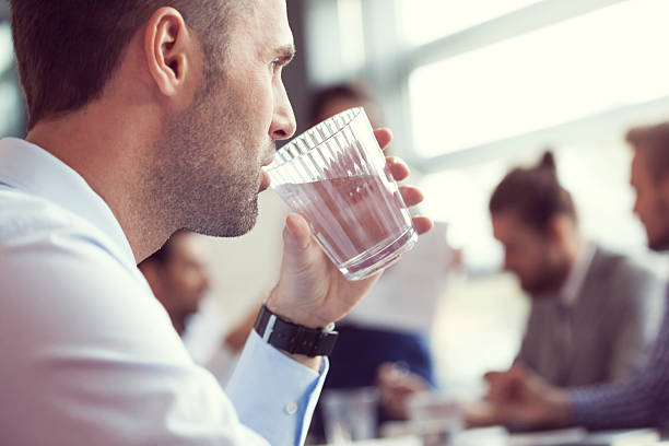 geschäftsmann trinken wasser im meetingraum - office water business meeting stock-fotos und bilder