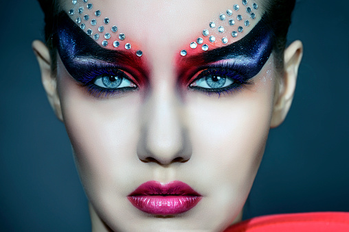 fashion woman portrait with gothic face paint and diamonds looking at camera.