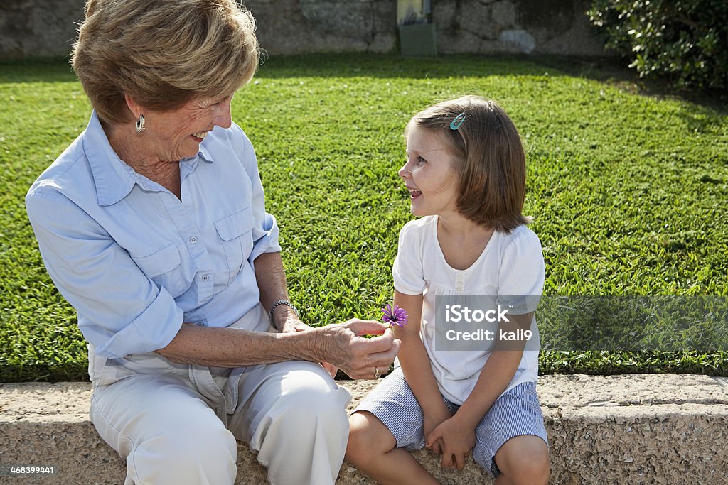 Abuela dando flores a granddaughter - Foto de stock de Cara a cara libre de derechos
