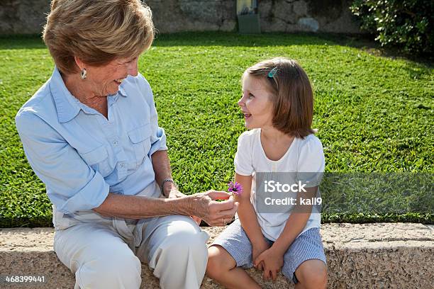 Abuela Dando Flores A Granddaughter Foto de stock y más banco de imágenes de Cara a cara - Cara a cara, Mujeres mayores, Niño