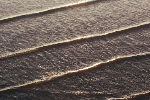 wave patterns created on a calm ocean with a backlit evening sun to highlight the movements