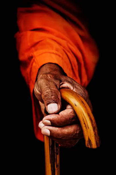 Old hand of holy man of Nepal holding a staff