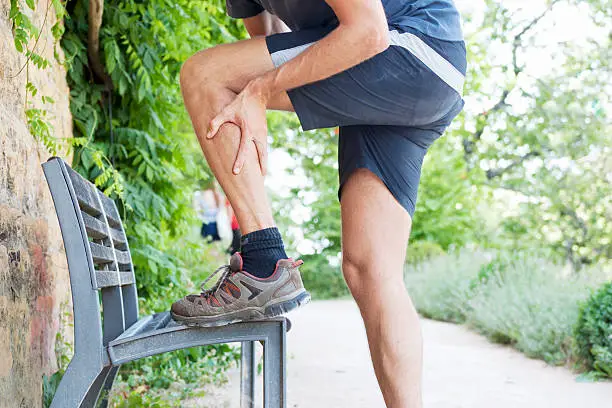 A male person, having a hurting calf, maybe due to a cramp during walking. XXL size image.