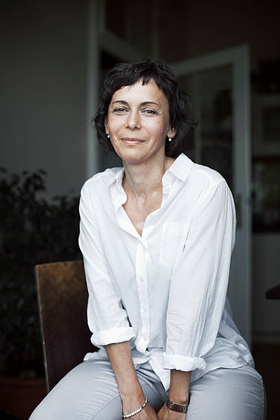 Smiling woman in white over a darkened backdrop stock photo