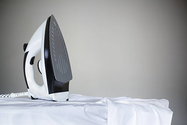 Iron on a shirt Ironing a white shirt with a steam iron on an ironing board with copy space drudgery photos stock pictures, royalty-free photos & images