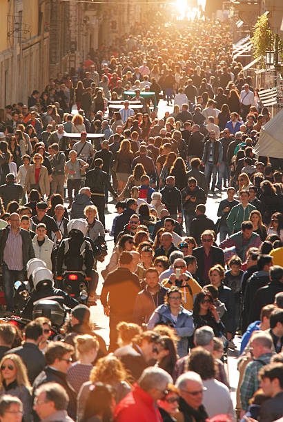 Large crowd of people on street in downtown Rome, vertical Large group of people crowding Rome's downtown streets in a sunny day. On a warm day the historic downtown of Rome, Italy, is flooded by people and tourists enjoying monuments and famous places. Vertical composition. bustling city stock pictures, royalty-free photos & images