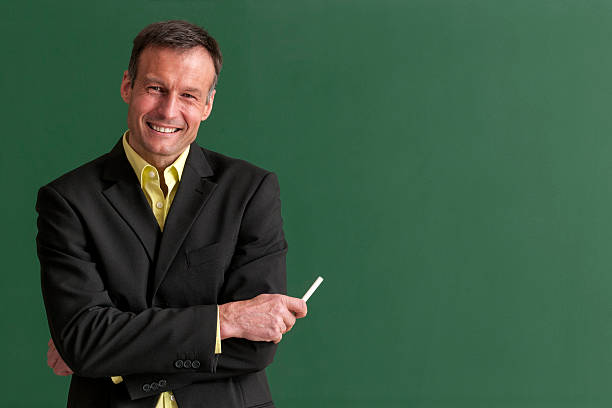 istock Middle-age male teacher smiling in front of blackboard 468420596