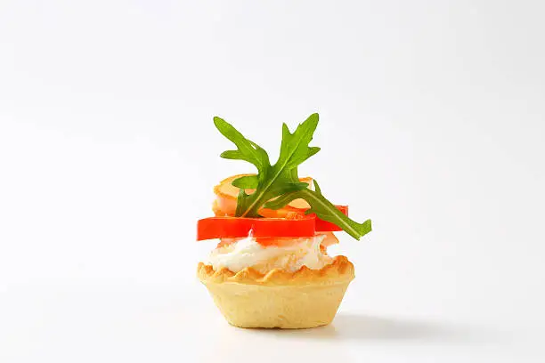 tartlet with cheese, ham, tomato and arugula leaves isolated on white background
