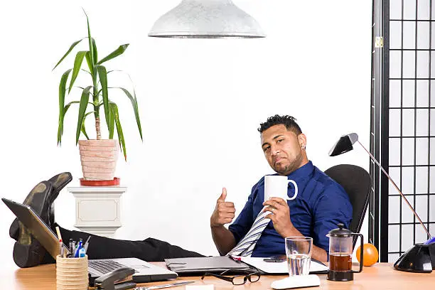 An image of an Indian office worker with a blue shirt behind his desk