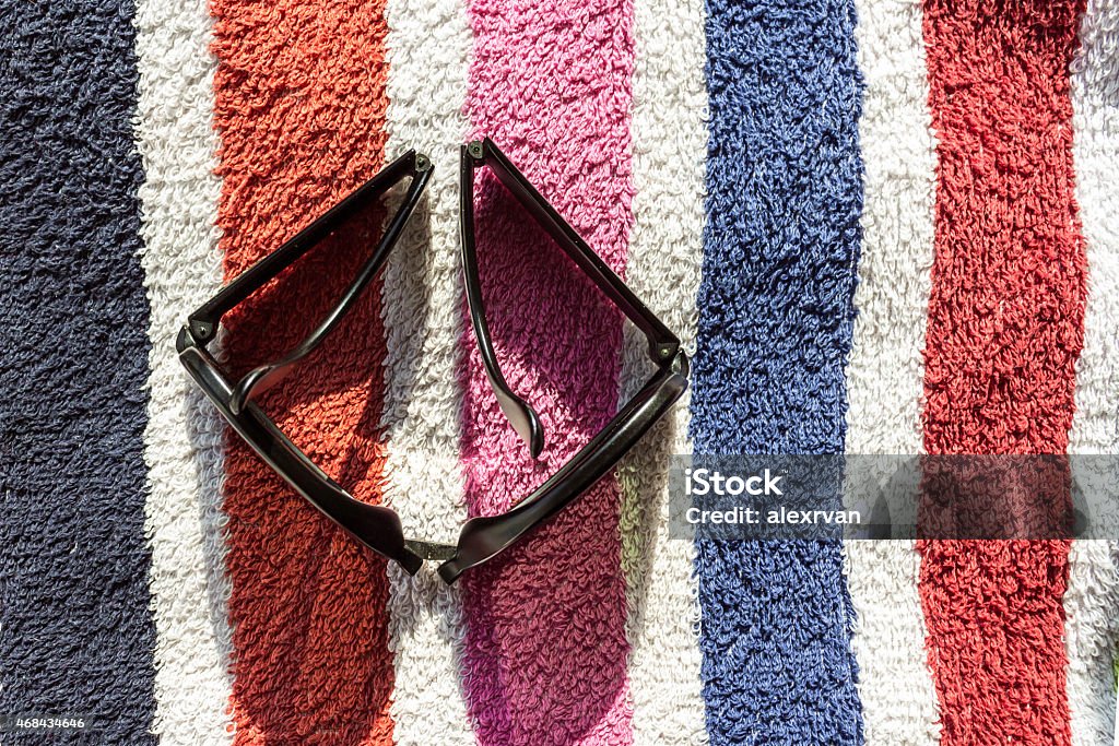 Folding Sunglasses Folding Shades on a beach towel with coloured stripes Bob Dylan Stock Photo