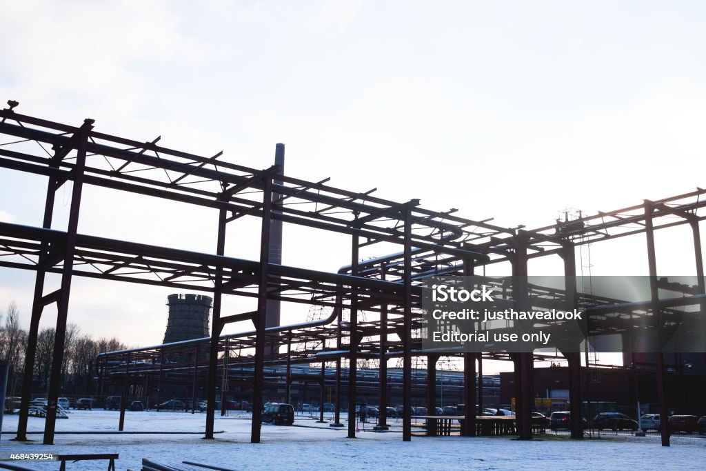 Winter morning at coke oven complex of Zeche Zollverein Essen, Germany - December 29, 2014: Winter morning shot of huge coke oven complex of Zeche Zollverein in Essen. On grounds cars of visitors are parked. A few people are between cars. 2015 Stock Photo