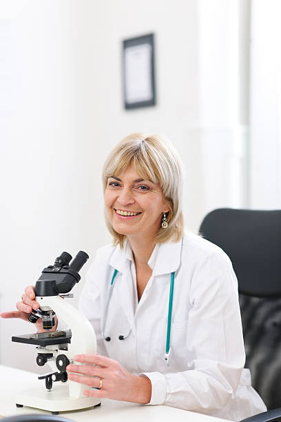 istock Smiling doctor woman working with microscope at laboratory 468440428