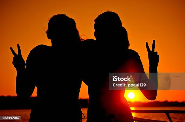 Zwei Mädchen Die Peacezeichen Bei Sonnenuntergang Am Meer Stockfoto und mehr Bilder von Fotografie