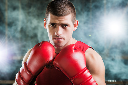 Portrait of a young male businessman in boxing gloves in the ring.