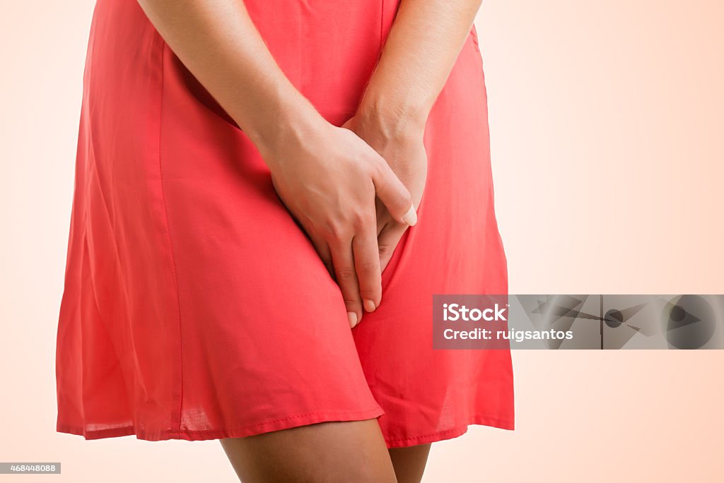 Woman in Need to Urinate Close up of a woman with hands holding her crotch, isolated in a pink background Human Groin Stock Photo