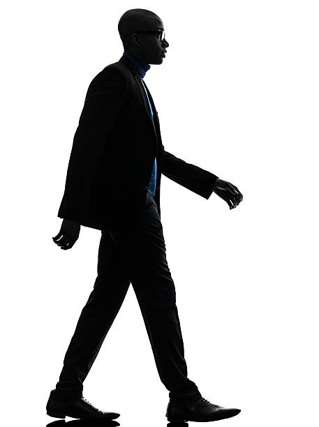 one african black man walking serious in silhouette studio on white background