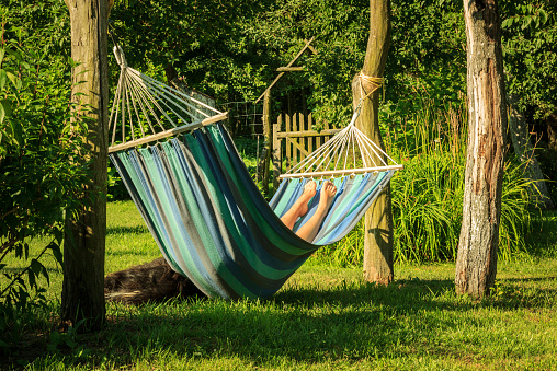 Woman relaxing on hammock during holiday. Vacation in nature. Feet close up. Relax in the garden. Sleeping woman in sunny day after work.