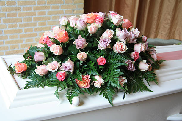 White coffin with pink sympathy flowers stock photo