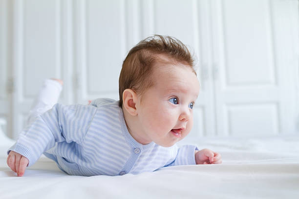 Smiling baby tummy time in a white nursery stock photo
