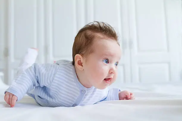 Photo of Smiling baby tummy time in a white nursery