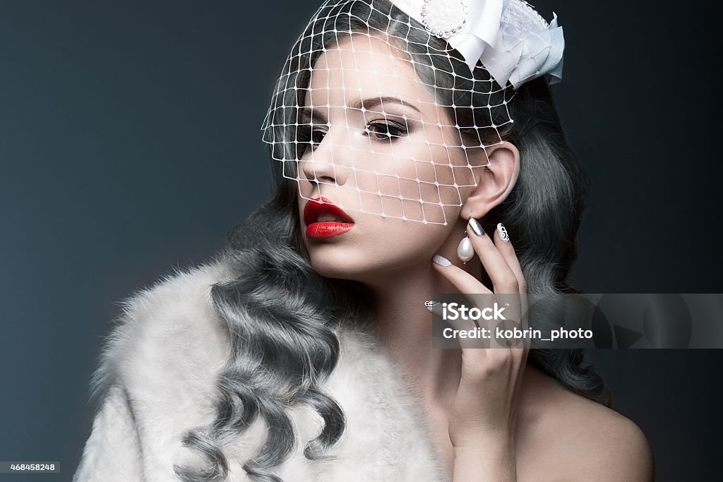 Elegant beautiful girl with silver curls and veil. Elegant beautiful girl with silver curls and a veil. Winter image. Beauty face. Picture taken in the studio on a gray background. Fashion Model Stock Photo