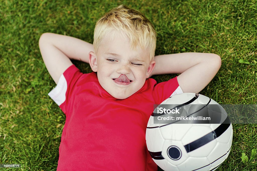 Menino de futebol relaxa na grama além de futebol - Foto de stock de Bola de Futebol royalty-free