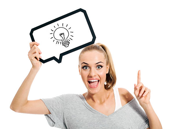 Conceptual portrait of excited blonde young woman in casual outfit holding thought bubble with drawn light bulb above her head. Standing against white background and screaming at camera with raised an index finger. Studio shot.