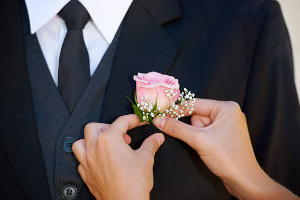 The final touch Cropped image of a groom getting his boutonniere adjusted before the wedding ceremony buttonhole flower stock pictures, royalty-free photos & images