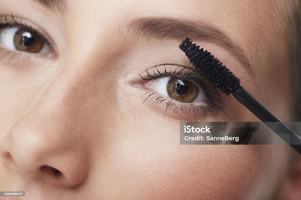 Portrait of young woman applying mascara, close up Accuracy Stock Photo