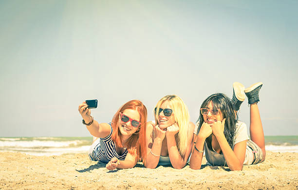 Happy girlfriends having fun and taking selfie at beach
