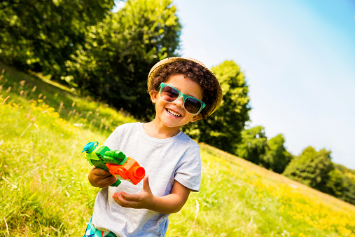Little kid smiling at camera with water gun in his hands