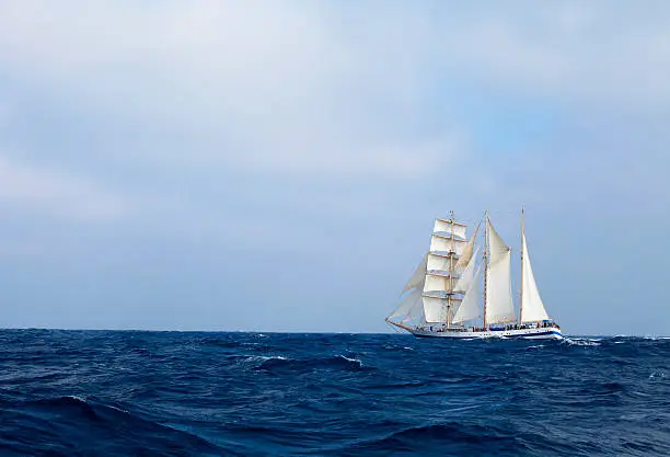 Barquentine with white sails in the calm sea