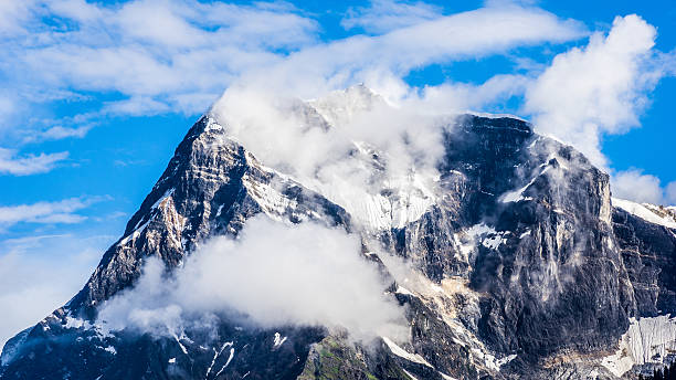 Snow mountain peak with clouds in blue sky stock photo