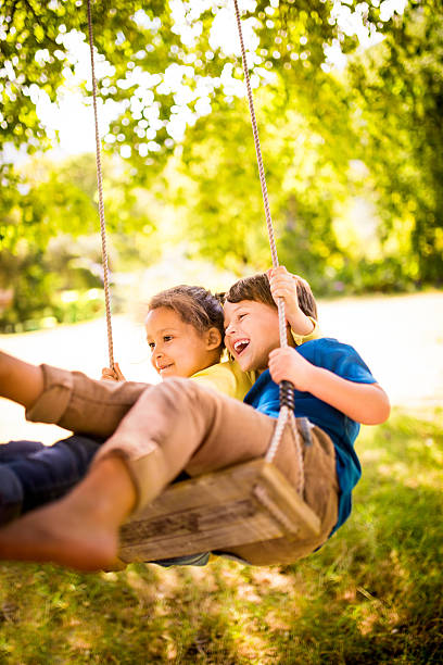 女の子と男の子の楽しみをチームにスイング高 - child tree cheerful offspring ストックフォトと画像