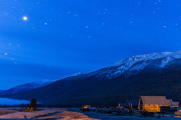 Nightscape of wooden house under snowcapped mountain stock photo