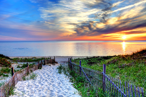 Path with beach fence leading to a secluded beach at sunset near Provincetown on Cape Cod. Cape Cod has some of the worlds most beautiful beaches. Cape Cod is famous, worldwide, as a coastal vacation destination with some of New England's premier beach destinations