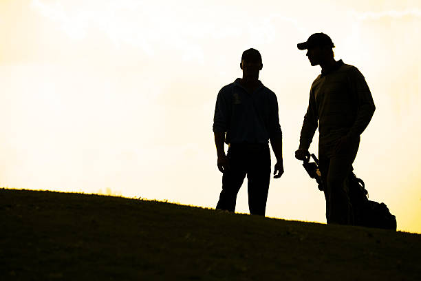 istock Silhouette of young men standing in golf course with trolley 468492212