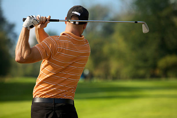 istock Young man swinging golf club, rear view 468492252