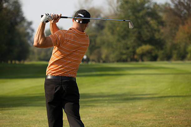 istock Young man swinging golf club, rear view 468492256