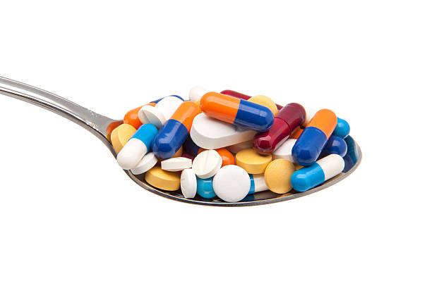 comprimidos y cápsulas en una cuchara - capsule vitamin pill red lecithin fotografías e imágenes de stock