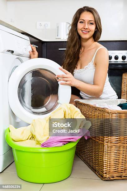 Smiling Woman Washing Clothes In Washer Stock Photo - Download Image Now - 2015, Adult, Adults Only